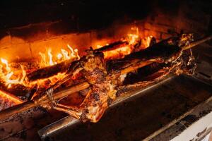 The lamb is cooked entirely on a spit on the fire. Cooking photo