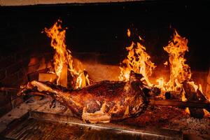 The lamb is cooked entirely on a spit on the fire. Cooking photo