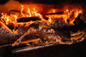 The lamb is cooked entirely on a spit on the fire. Cooking photo
