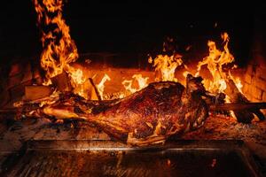 The lamb is cooked entirely on a spit on the fire. Cooking photo