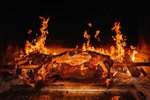 The lamb is cooked entirely on a spit on the fire. Cooking photo