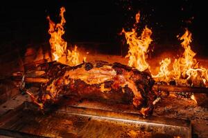 The lamb is cooked entirely on a spit on the fire. Cooking photo