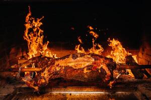 The lamb is cooked entirely on a spit on the fire. Cooking photo