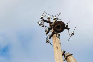 One old concrete street pole with a rusty iron part at the top and cut wires, Installation or dismantling of the power grid. A broken energy pillar photo