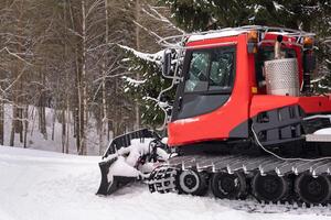 A snowplow on red tracks standing in winter in the forest near the barn photo
