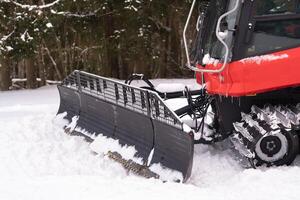The bucket of a snowplow on tracks, standing in the forest in winter photo