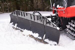 The bucket of a snowplow on tracks, standing in the forest in winter photo