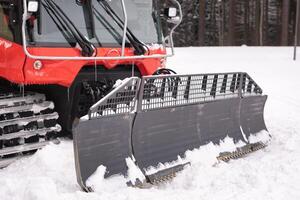 The bucket of a snowplow on tracks, standing in the forest in winter photo