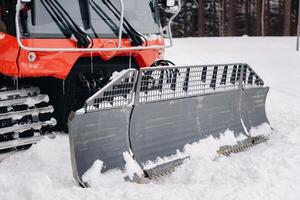 The bucket of a snowplow on tracks, standing in the forest in winter photo