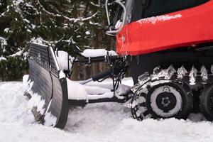 The bucket of a snowplow on tracks, standing in the forest in winter photo
