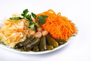 pickled vegetables, cucumber, carrot, garlic, cabbage on a plate on a white isolated background photo
