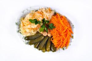 pickled vegetables, cucumber, carrot, garlic, cabbage on a plate on a white isolated background photo