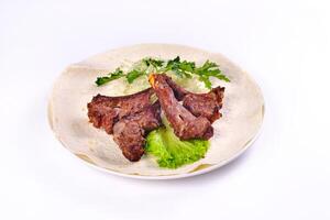 Meat kebab on ribs on lavash with onions and cabbage on a white plate, on an isolated white background photo