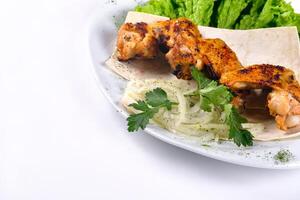 Chicken meat on pita bread with vegetables on a white plate on a white isolated background photo