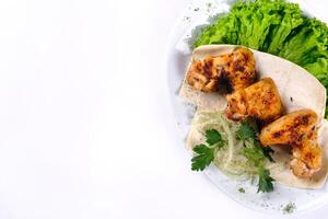 Chicken meat on pita bread with vegetables on a white plate on a white isolated background photo