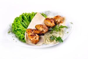 Chicken meat on pita bread with vegetables on a white plate on a white isolated background photo
