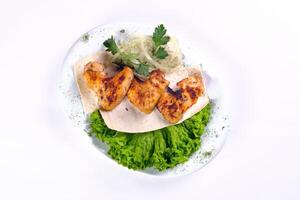 Chicken meat on pita bread with vegetables on a white plate on a white isolated background photo