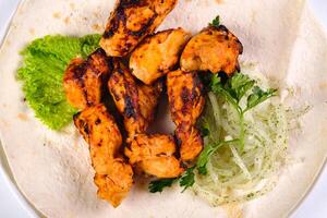 Chicken meat on pita bread with vegetables on a white plate on a white isolated background photo