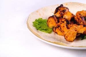 Chicken meat on pita bread with vegetables on a white plate on a white isolated background photo