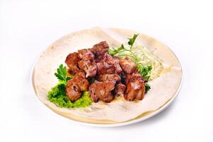 Pork shish kebab on lavash lies in a white plate on a white isolated background photo