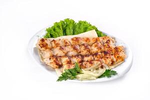 Homemade kebab on skewers with pita bread, onions, cabbage, vegetables, on a white plate on an isolated white background photo