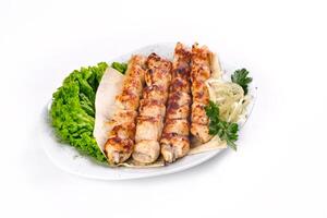 Homemade kebab on skewers with pita bread, onions, cabbage, vegetables, on a white plate on an isolated white background photo