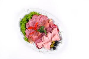 Ham and sausage cut into slices on a plate on a white isolated background photo