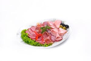 Ham and sausage cut into slices on a plate on a white isolated background photo