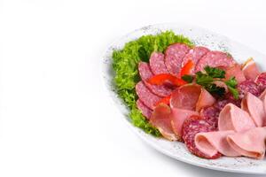 Ham and sausage cut into slices on a plate on a white isolated background photo