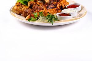 assorted meat on pita bread with vegetables and sauces on a white plate on a white isolated background photo