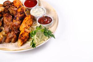 assorted meat on pita bread with vegetables and sauces on a white plate on a white isolated background photo