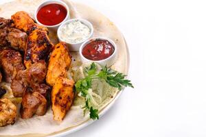 assorted meat on pita bread with vegetables and sauces on a white plate on a white isolated background photo