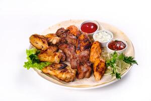 assorted meat on pita bread with vegetables and sauces on a white plate on a white isolated background photo