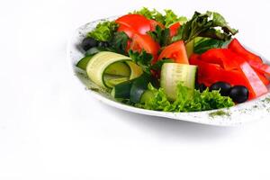 Delicious vegetable salad of tomatoes and cucumbers with olives on a plate on an isolated background photo