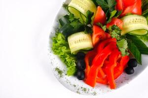 Delicious vegetable salad of tomatoes and cucumbers with olives on a plate on an isolated background photo