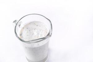 A glass of ayran with dill and parsley, highlighted on a white isolated background. Cold yogurt drink photo