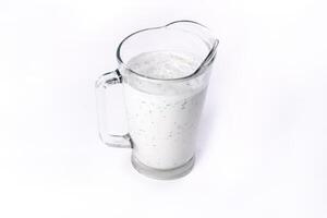 A glass of ayran with dill and parsley, highlighted on a white isolated background. Cold yogurt drink photo