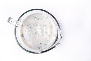 A glass of ayran with dill and parsley, highlighted on a white isolated background. Cold yogurt drink photo