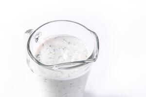 A glass of ayran with dill and parsley, highlighted on a white isolated background. Cold yogurt drink photo
