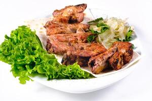 Meat kebab on ribs on lavash with onions and cabbage on a white plate, on an isolated white background photo
