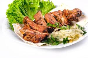 Meat kebab on ribs on lavash with onions and cabbage on a white plate, on an isolated white background photo