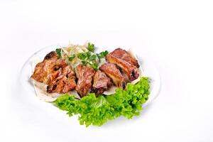 Meat kebab on ribs on lavash with onions and cabbage on a white plate, on an isolated white background photo
