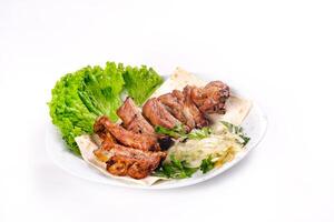 Meat kebab on ribs on lavash with onions and cabbage on a white plate, on an isolated white background photo