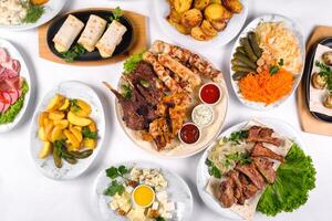 A covered table with many different dinner dishes. Lots of food on a white isolated background photo