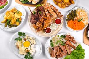 A covered table with many different dinner dishes. Lots of food on a white isolated background photo
