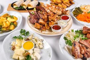 A covered table with many different dinner dishes. Lots of food on a white isolated background photo