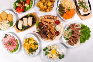 A covered table with many different dinner dishes. Lots of food on a white isolated background photo