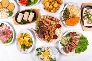 A covered table with many different dinner dishes. Lots of food on a white isolated background photo