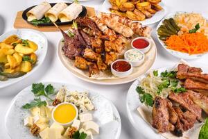 A covered table with many different dinner dishes. Lots of food on a white isolated background photo