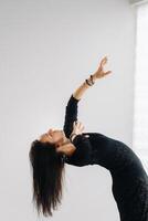 A girl in a black dress moves in a dance on a gray background. Dynamic dance photo